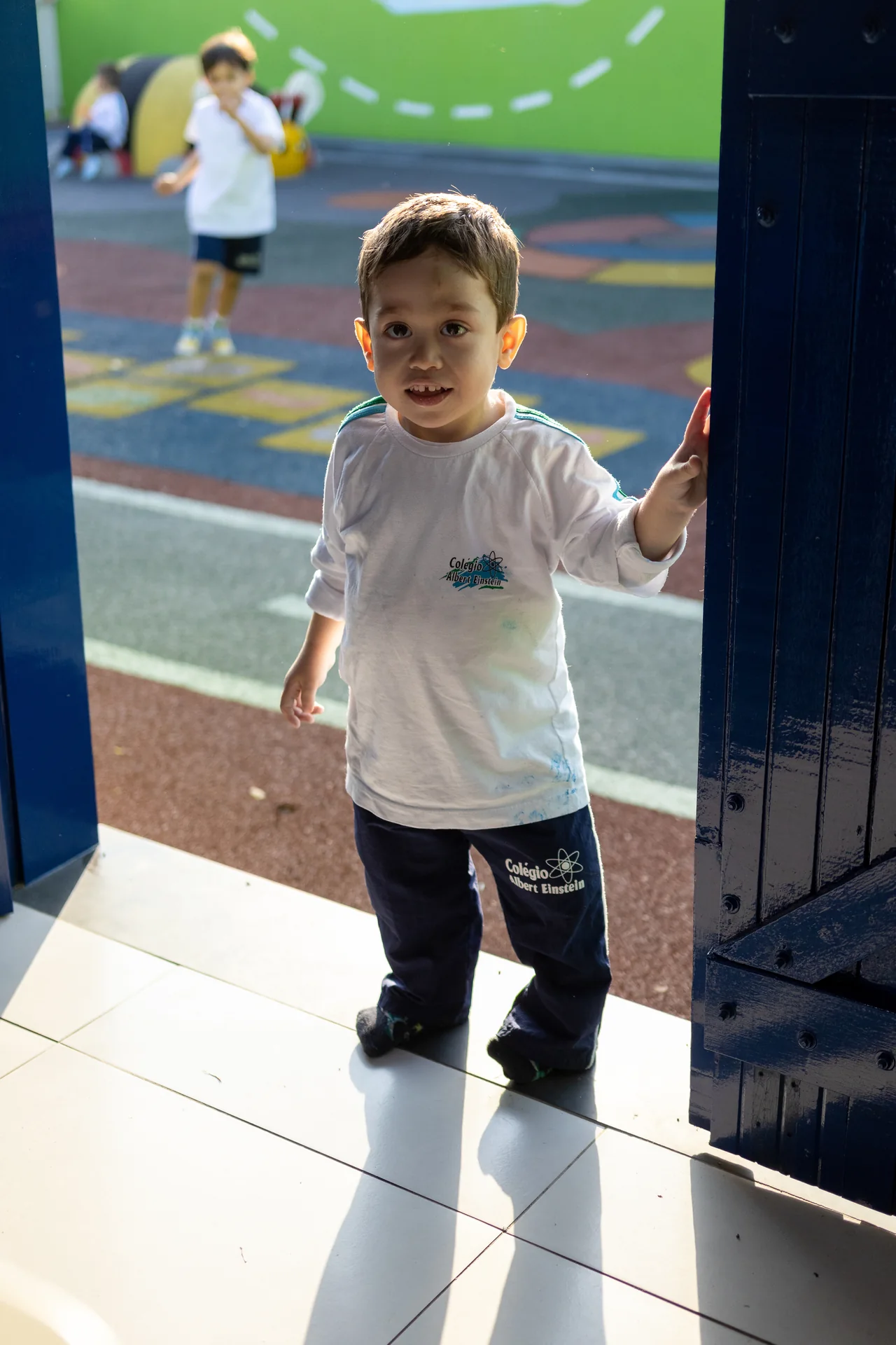 Criança entrando na sala, com playground ao fundo
