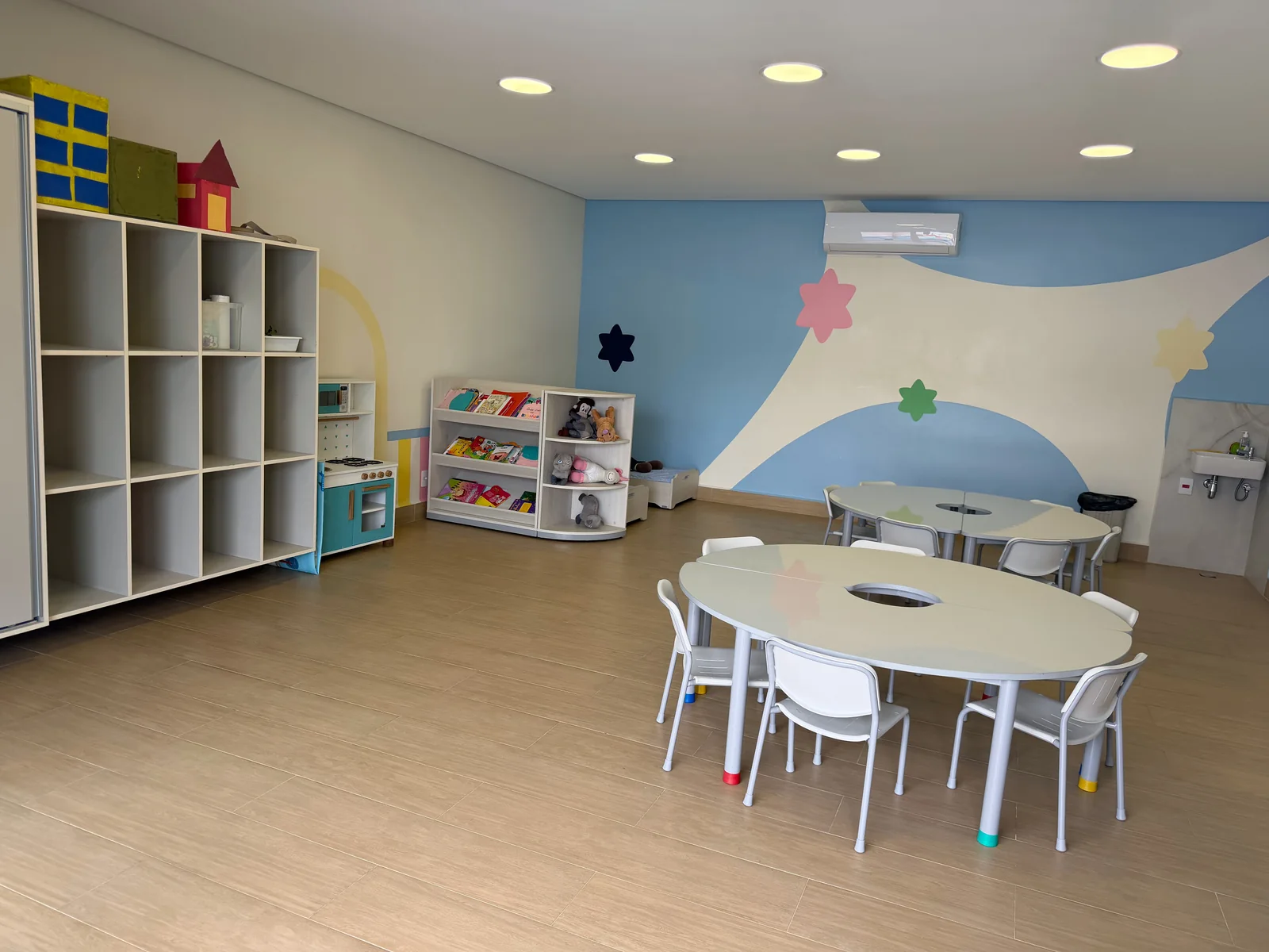 Sala infantil com livros, mesas e brinquedos