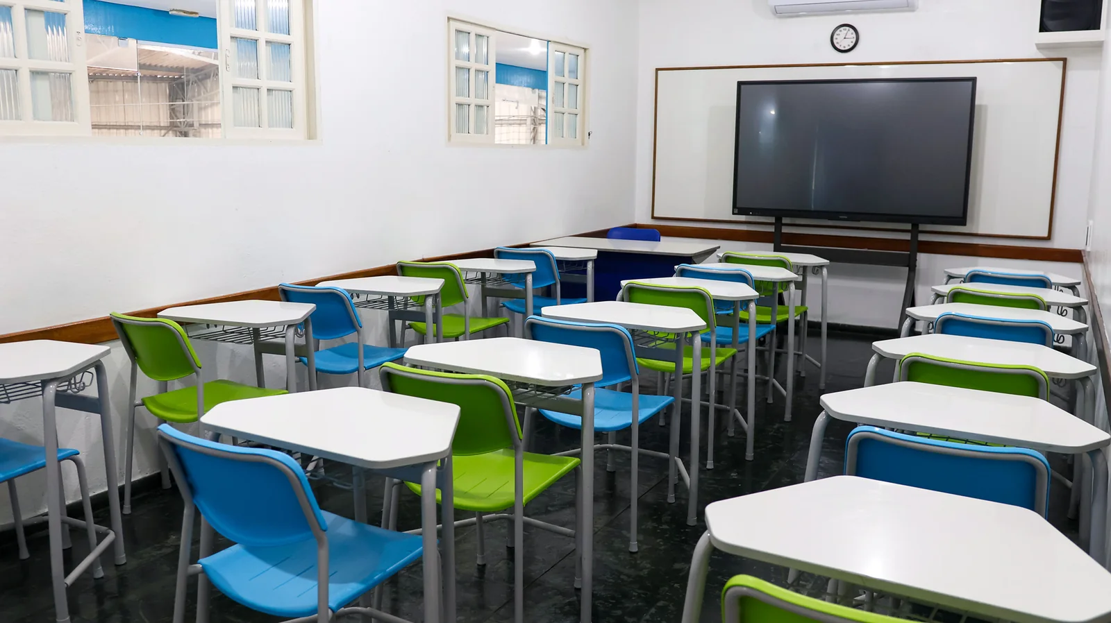 Sala de aula com carteiras e tela multimídia