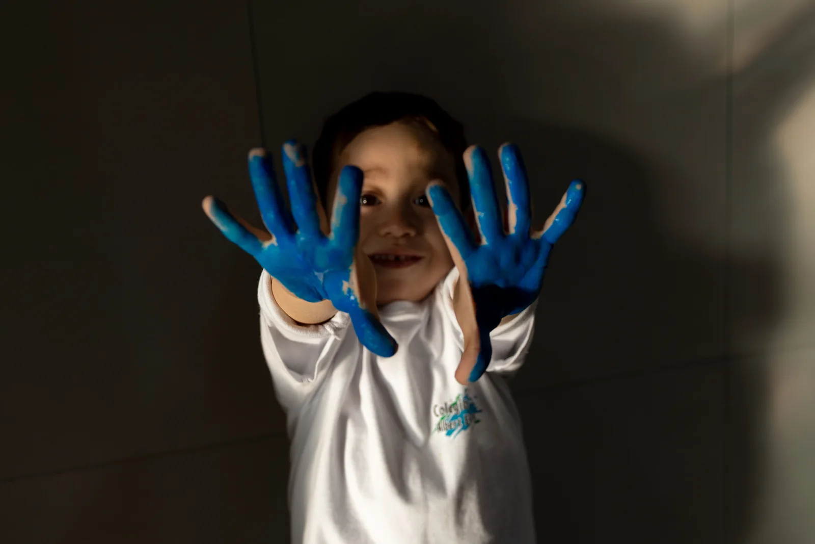 Criança mostrando as mãos pintadas em uma atividade