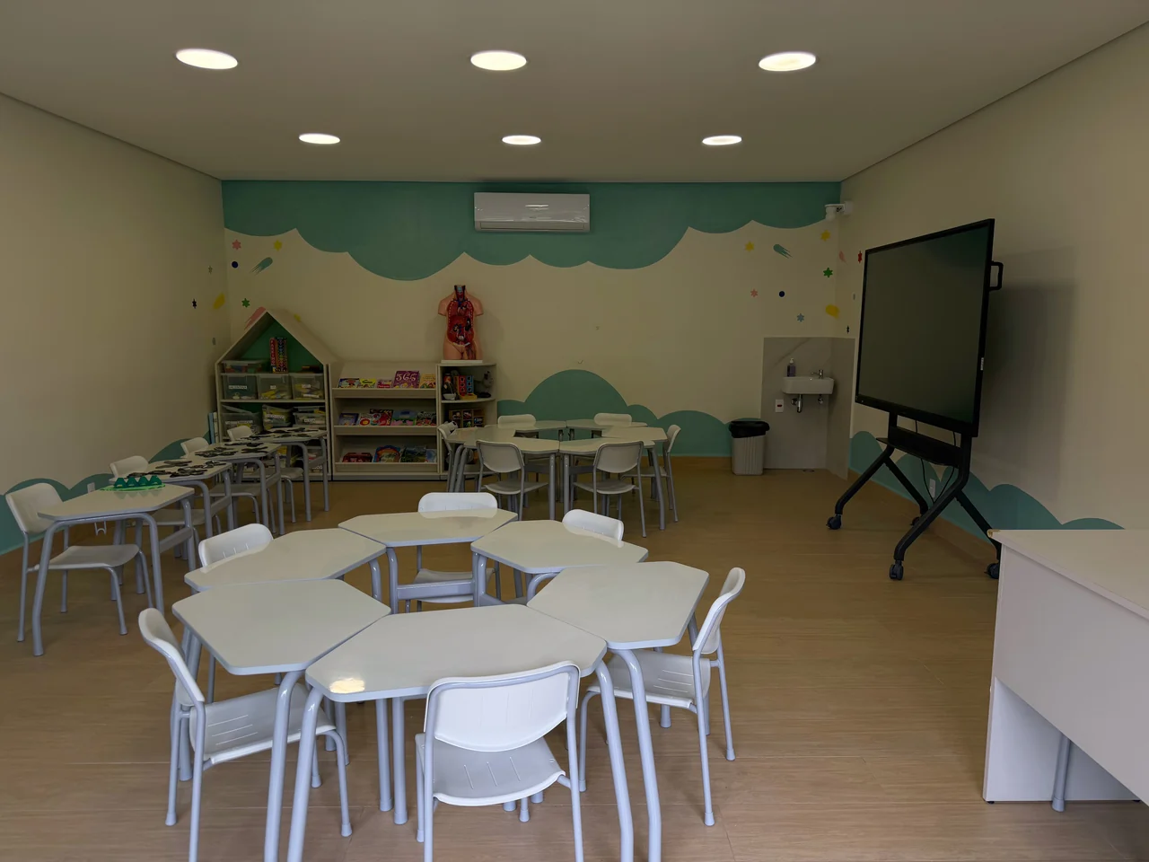 Sala de atividades do Colégio Albert Einstein com mesas coletivas
